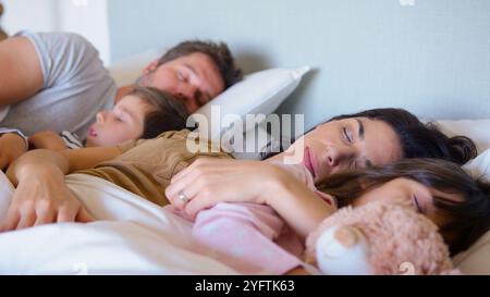 Friedliche Eltern Mit Kindern Kuschelspielzeug, Die Gemeinsam Im Bett Schlafen Stockfoto
