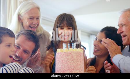 Die Familie Der Mehrgenerationen Feiert Den Geburtstag Mit Ihrer Enkelin Zu Hause, Während Sie Kerzen Ausbläst Stockfoto