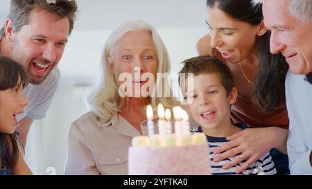 Familie Mit Mehreren Generationen Feiert Geburtstag Mit Großmutter Zu Hause, Während Sie Kerzen Ausbläst Stockfoto