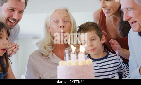 Familie Mit Mehreren Generationen Feiert Geburtstag Mit Großmutter Zu Hause, Während Sie Kerzen Ausbläst Stockfoto