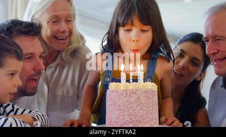 Die Familie Der Mehrgenerationen Feiert Den Geburtstag Mit Ihrer Enkelin Zu Hause, Während Sie Kerzen Ausbläst Stockfoto