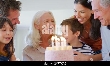 Familie Mit Mehreren Generationen Feiert Geburtstag Mit Großmutter Zu Hause, Während Sie Kerzen Ausbläst Stockfoto