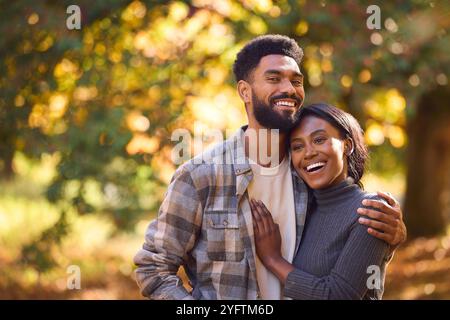 Porträt Des Liebenden Jungen Paares, Das Sich Vor Dem Hintergrund Von Herbstlaub Im Garten Oder Auf Dem Land Umarmt Stockfoto