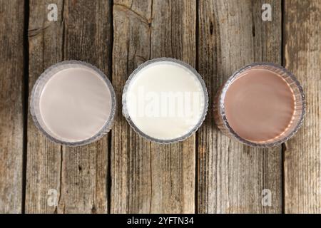 Verschiedene leckere Proteincocktails in Gläsern auf Holztisch, flach gelegt Stockfoto