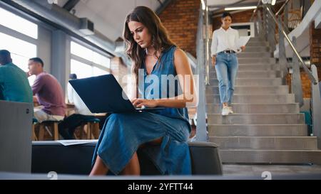 Junge Geschäftsfrau Sitzt Und Arbeitet Am Laptop In Einem Modernen Großraumbüro Stockfoto