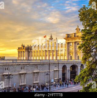 Hauptfassade des Königspalastes von Madrid bei Sonnenuntergang. Touristen versammeln sich vor dem Prince Gate. Madrid, Spanien. Stockfoto