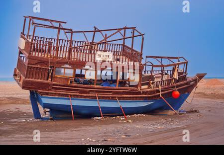 Ein verwittertes Holzboot am Seeb Beach, Maskat, Oman. Stockfoto