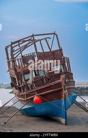 Ein verwittertes Holzboot am Seeb Beach, Maskat, Oman. Stockfoto