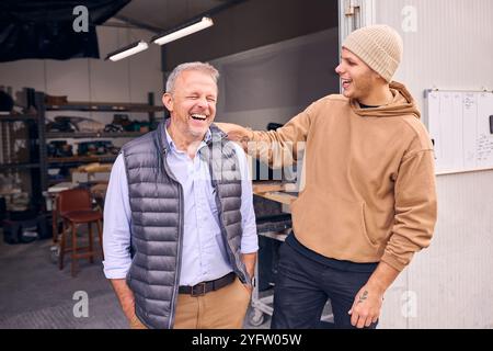 Lächelnder Manager Und Männlicher Arbeiter Stehen Vor Der Tür Der Betonwerkstatt Stockfoto