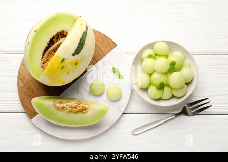 Melonenkugeln in der Schüssel und frisches Obst auf weißem Holztisch, flach gelegt Stockfoto