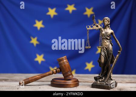 Figur der Justizdame und der Hammer des Richters auf Holztisch vor der Flagge der Europäischen Union Stockfoto