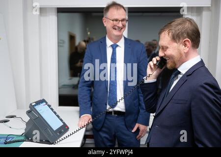 Freital, Deutschland. November 2024. Günther Welsch (l), Leiter der Abteilung Kryptotechnologie, erklärt dem sächsischen Ministerpräsidenten Michael Kretschmer (CDU) ein Telefon für die Hochsicherheits-Telefonielösung zur Übermittlung von Verschlusssachen beim Bundesamt für Sicherheit in der Informationstechnik (BSI). Die Telefonielösung ist für den Testbetrieb in Sachsen vorgesehen. Quelle: Sebastian Kahnert/dpa/Alamy Live News Stockfoto