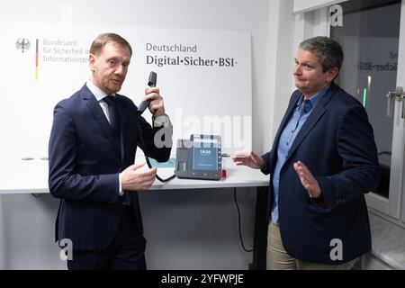 Freital, Deutschland. November 2024. Michael Kretschmer (CDU), Ministerpräsident von Sachsen, hält neben der BSI-Präsidentin Claudia Plattner ein Telefon für die Hochsicherheits-Telefonielösung zur Kommunikation von Verschlusssachen beim Bundesamt für Sicherheit in der Informationstechnik (BSI). Die Telefonielösung wird in Sachsen getestet. Quelle: Sebastian Kahnert/dpa/Alamy Live News Stockfoto