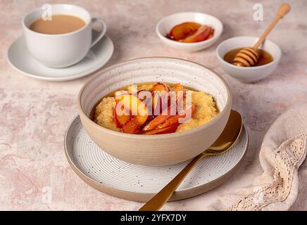 Lebensmittelfotografie von Hirsebrei mit karamelisiertem Pfirsich, Nektarine mit Agavendicksaft, Honig, Tee mit Mandelmilch Stockfoto