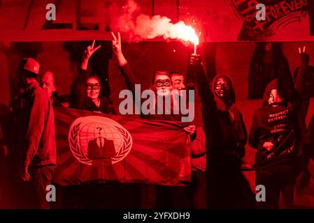 Rotes Flare entzündete sich beim Million Mask March, Anonym für die stimmlose Demonstration durch London bei Guy Fawkes Night, 5. November. Flag Stockfoto