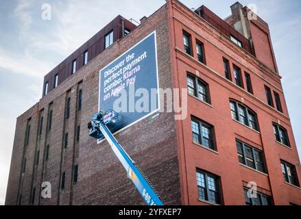 Ein Schildermaler erstellt am Montag, den 28. Oktober 2024, eine Plakatwand für Klarna, den schwedischen Online-Zahlungsabwickler, und Apple Pay im Meatpacking District in New York. (© Richard B. Levine) Stockfoto