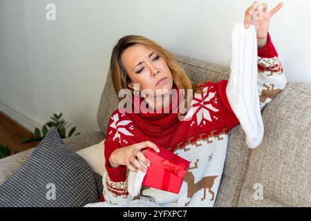 Eine Frau schaut auf das Weihnachtsgeschenk. Das Konzept der Weihnachtsgeschenke Stockfoto