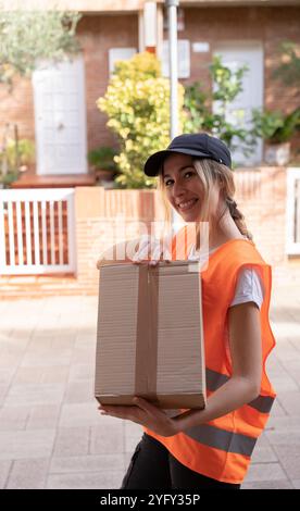 Junge, schöne blonde Frau, die Lieferboxen hält. Lieferung nach Hause. Vertikale Fotografie Stockfoto