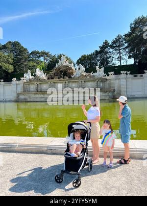 Eine Familie genießt einen sonnigen Tag in einem malerischen Park und bewundert einen historischen Brunnen im Schloss Schönbrunn, Österreich. Kleine Kinder sind anwesend, mit einem i Stockfoto