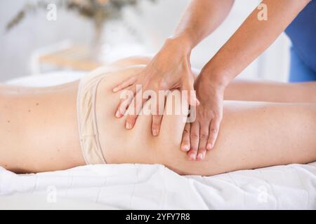 Professionelle Masseurin bei der Massage von Oberschenkel und Gesäß gegen Cellulite an die Frau Stockfoto