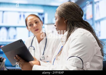 Mitarbeiter des Gesundheitswesens treffen sich in einer Klinik, um Röntgendaten zu analysieren, und treffen sich, um Röntgenaufnahmen und Krankenhausaufzeichnungen zu untersuchen. Lizenzierte Experten arbeiten an Behandlungsplänen und Teamwork zusammen. Stockfoto