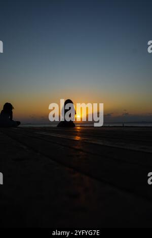 Salvador, Bahia, Brasilien - 22. Oktober 2024: Unbekannte Menschen in Silhouette genießen den dramatischen Sonnenuntergang in Porto da Barra. Salvador, Bahia. Stockfoto