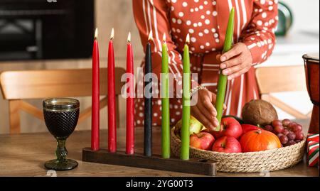 Junge afroamerikanische Frau mit Kerzen, die Kwanzaa in der Küche feiert Stockfoto