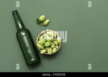Schüssel mit Hopfenzapfen und Flasche Bier auf grünem Hintergrund Stockfoto