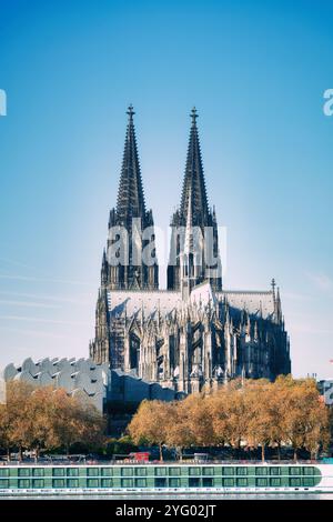 Der majestätische kölner Dom im Herbst mit den markanten Wellen des Museums Ludwig und Ausflugsbooten im Vordergrund Stockfoto