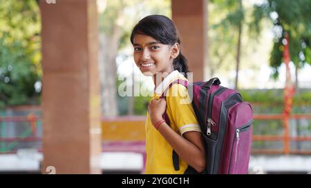 Glückliche indische Grundschüler, die am Schreibtisch im Klassenzimmer sitzen und in Notizbuch mit Bleistift schreiben, Prüfung und Test, weibliche Lehrerin Stockfoto