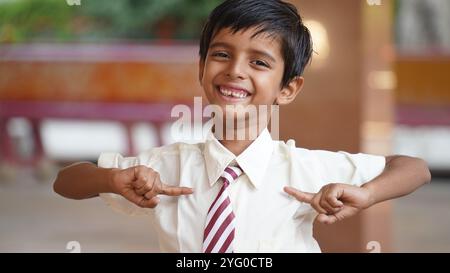 Glückliche indische Grundschüler, die am Schreibtisch im Klassenzimmer sitzen und in Notizbuch mit Bleistift schreiben, Prüfung und Test, weibliche Lehrerin Stockfoto