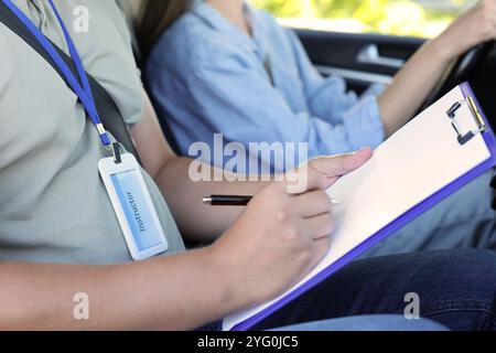 Fahrschule. Student, der die Fahrprüfung mit dem Prüfer im Auto besteht, Nahaufnahme Stockfoto
