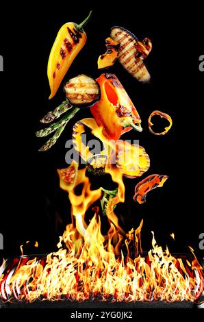 Gegrilltes Gemüse in der Luft über Flamme auf schwarzem Hintergrund Stockfoto