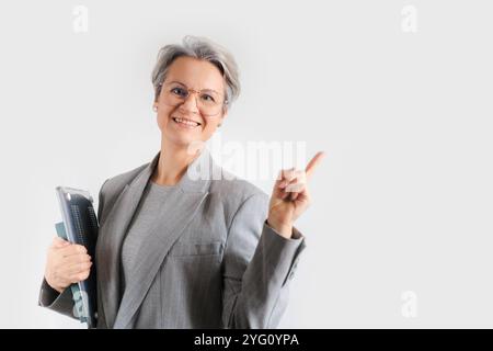 Eine europäische Frau mittleren Alters mit grauem Haar trägt eine formelle graue Jacke und Brille. Stockfoto