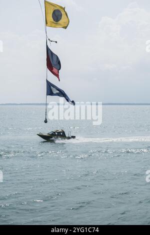 Ein Schnellboot bewegt sich direkt unter dem Pendel für das Flaggenseil des Schiffes Bima Suci. Semayang Harbor, Balikpapan, East Borneo, Indonesien Stockfoto