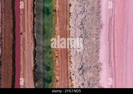 Pink Lake, aufgenommen mit einer Drohne aus der Vogelperspektive, mit mehrschichtigen Strukturen der Straße, des Wassers, des Schmutzes und des rosa Salzsees. Stockfoto