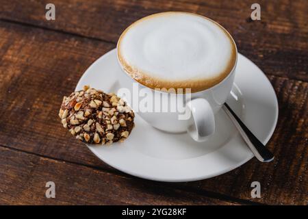 Cappuccino-Kaffee in weißer Porzellantasse auf Holztisch Stockfoto