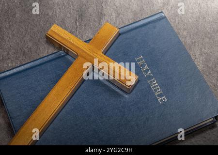 Religionskreuz und Buch der Heiligen Bibel. Es liegt auf dem Tisch. Symbol des Glaubens und der Anbetung in Gott. Religiöser christlicher Dienst, Feiertag oder Konzept Stockfoto