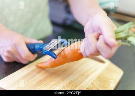 Frauenhände schälen frische Orangenmohren in einer Küche Stockfoto