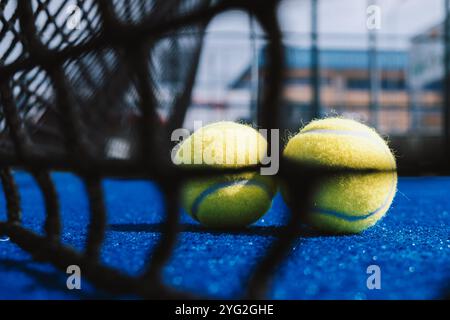 Unscharfe Nahaufnahme eines Padel-Tennisplatz-Netzes und zwei Bälle dahinter Stockfoto