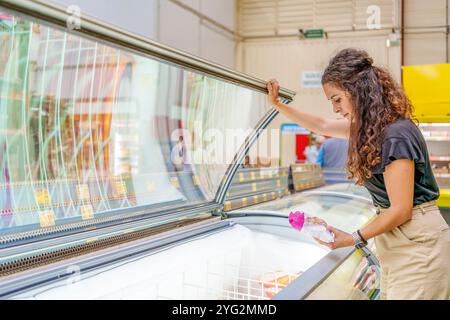 Frau mittleren Alters, die Tiefkühlprodukte in der Tiefkühlabteilung des Supermarktes auswählt Stockfoto