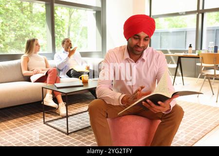 Geschäftsmann trägt Sikh-Turban und liest Dokumente im Büro Stockfoto