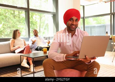 Geschäftsmann mit Sikh-Turban und Laptop im Büro Stockfoto