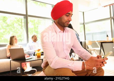 Geschäftsmann mit Sikh-Turban und Telefon im Büro Stockfoto