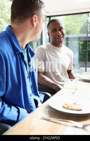 Lächelnde Männer sitzen am Tisch Stockfoto