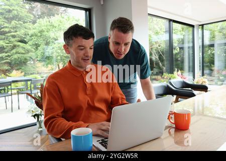 Lächelnde Männer, die auf den Laptop schauen Stockfoto