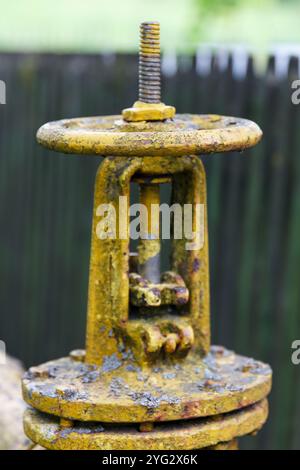 Gasleitung mit einem großen alten gelben Ventilkran. Industriegasleitung entlang Zaun verlegt, Vergasung der Bevölkerung. Stockfoto