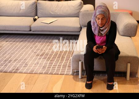Frau mit Smartphone sitzt auf Sofa in einem modernen Büro Stockfoto