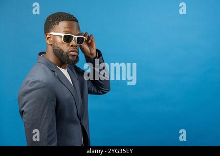 Schwarzer Mann mit Sonnenbrille auf blauem Hintergrund Stockfoto