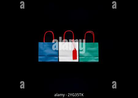 Bunte Einkaufstaschen mit rotem Preisschild auf weißer Farbe, eine auf schwarzem Hintergrund für das Konzept des Black Friday Shopping Day. Stockfoto